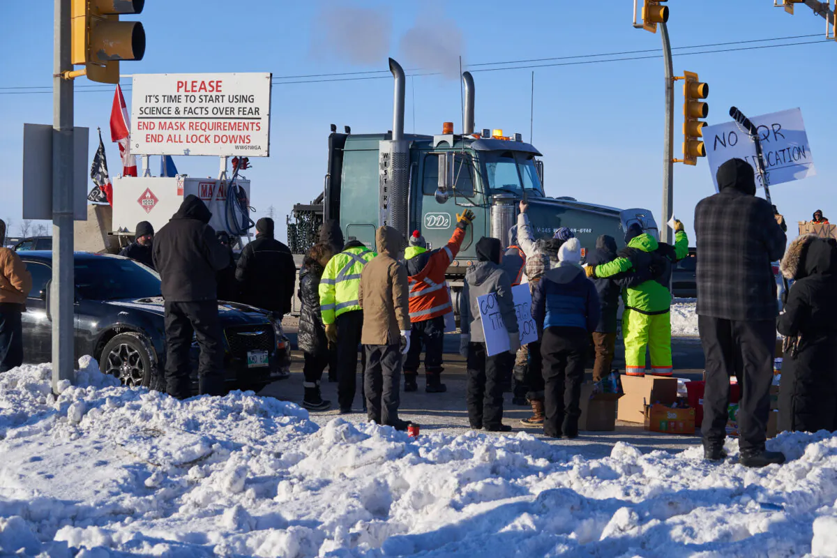 Supporters of Canadian truck drivers protesting the COVID-19 vaccine mandate cheer on a convoy of trucks on their way to Ottawa, on the Trans-Canada Highway west of Winnipeg on Jan. 25, 2022. (The Canadian Press/David Lipnowski)