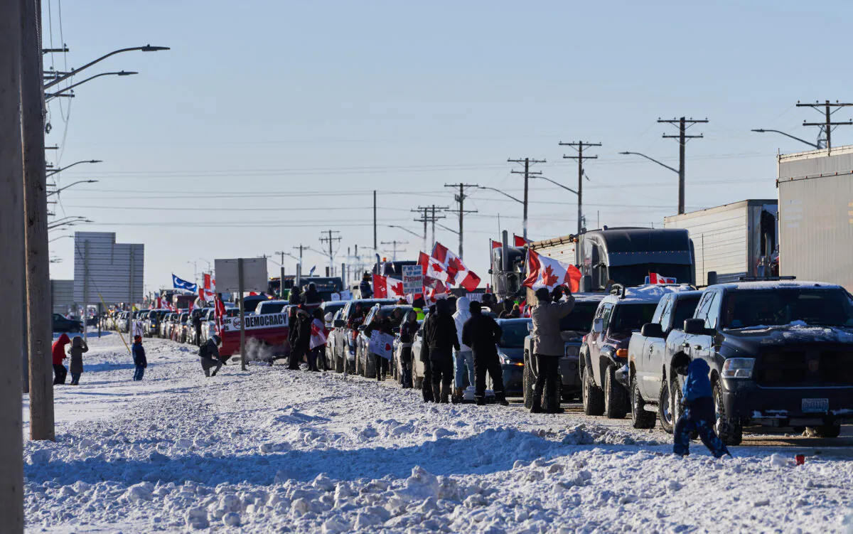 Supporters of Canadian truck drivers protesting the COVID-19 vaccine mandate cheer on a convoy of trucks on their way to Ottawa, on the Trans-Canada Highway west of Winnipeg, Manitoba, on Jan. 25, 2022. (David Lipnowski/The Canadian Press)