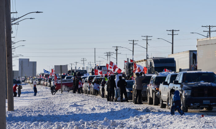 Supporters of Canadian truck drivers protesting the COVID-19 vaccine mandate cheer on a convoy of trucks on their way to Ottawa, on the Trans-Canada Highway west of Winnipeg, Manitoba, on Jan. 25, 2022. (David Lipnowski/The Canadian Press)