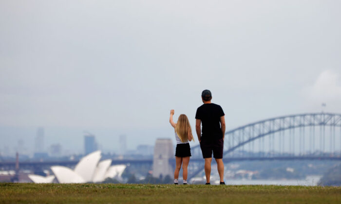A girl waves as her father looks on from a park overlooking Sydney Harbour in Australia, on Dec. 29, 2021. (Jenny Evans/Getty Images)