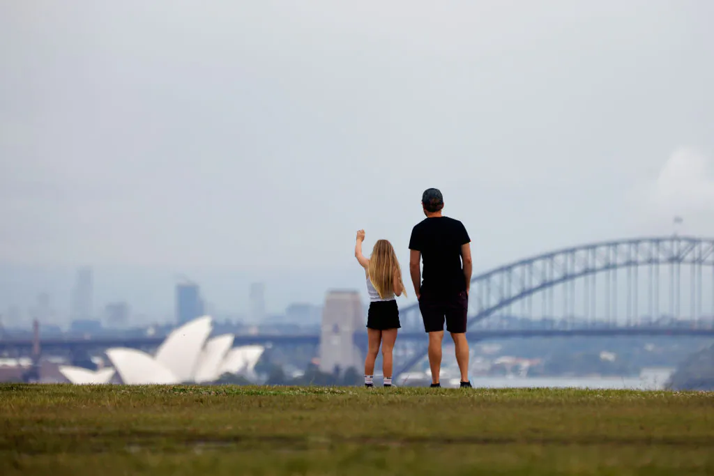 A girl waves as her father looks on from a park overlooking Sydney Harbour in Australia, on Dec. 29, 2021. (Jenny Evans/Getty Images)