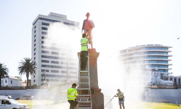 Workers wash off red paint that was poured on a statue of Captain Cook at St. Kilda beach in Melbourne, Australia, on Jan. 26, 2022. (Diego Fedele/Getty Images)