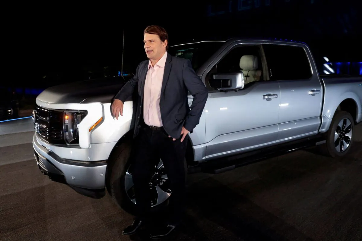 Ford CEO Jim Farley poses with the all-electric Ford F-150 Lightning pickup truck during the unveiling at the company's world headquarters in Dearborn, Mich., on May 19, 2021. (Rebecca Cook/Reuters)