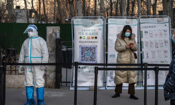 A medical worker stands in protective equipment as a client registers for a nucleic acid test at a private outdoor clinic in Beijing, China, on Dec. 27, 2021. (Kevin Frayer/Getty Images)