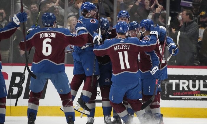 Colorado Avalanche players celebrate with defenseman Cale Makar after his power-play goal in overtime of an NHL hockey game against the Boston Bruins in Denver, on Jan. 26, 2022. (David Zalubowski/AP Photo)