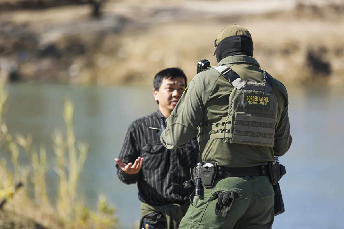 A Border Patrol agent talks to a Chinese man who just waded across the Rio Grande from Mexico into Eagle Pass, Texas, on Jan. 25, 2022. (Charlotte Cuthbertson/The Epoch Times)