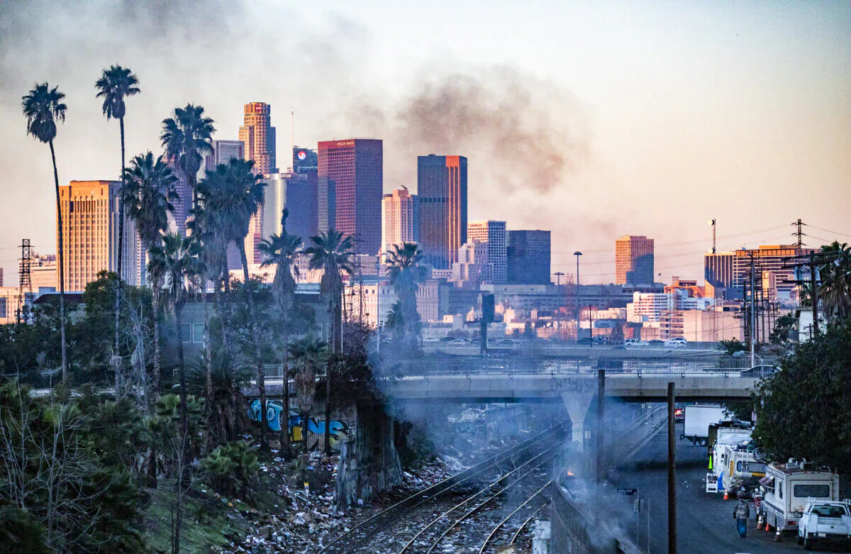 A fire burns in a homeless encampment while shredded boxes cover railroad tracks after ongoing theft in Los Angeles, Calif., on Jan. 20, 2022. (John Fredricks/The Epoch Times)