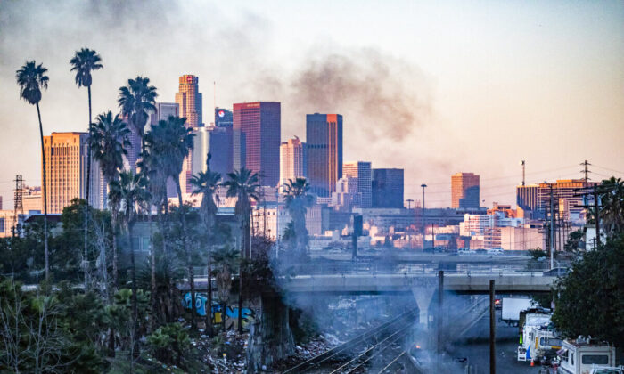 A fire burns in a homeless encampment while shredded boxes cover railroad tracks after ongoing theft in Los Angeles, Calif., on Jan. 20, 2022. (John Fredricks/The Epoch Times)