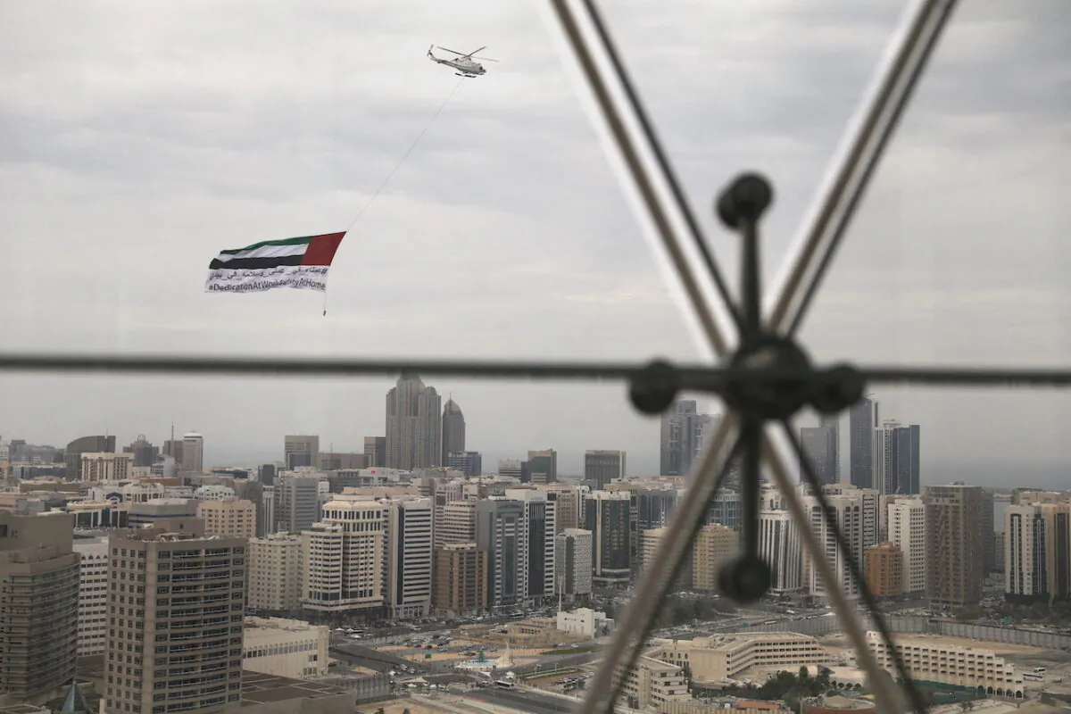 A helicopter flies over the downtown skyline of Abu Dhabi, United Arab Emirates, April 20, 2020. (Christopher Pike/Reuters)
