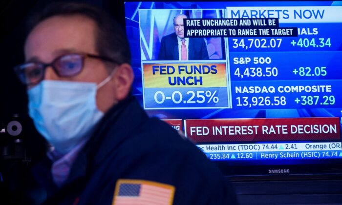 A screen displays the Fed rate announcement as a specialist trader works at his post on the floor of the New York Stock Exchange (NYSE) in New York City, on Jan. 26, 2022. (Brendan McDermid/Reuters)