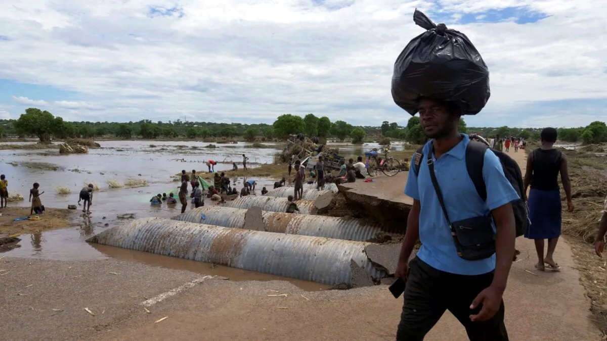 A man carries goods on his head as he walks past a flooded road damaged by tropical storm Ana at Thabwa village, in Chikwawa district, southern Malawi, on Jan. 26, 2022. (Eldson Chagara/Reuters)