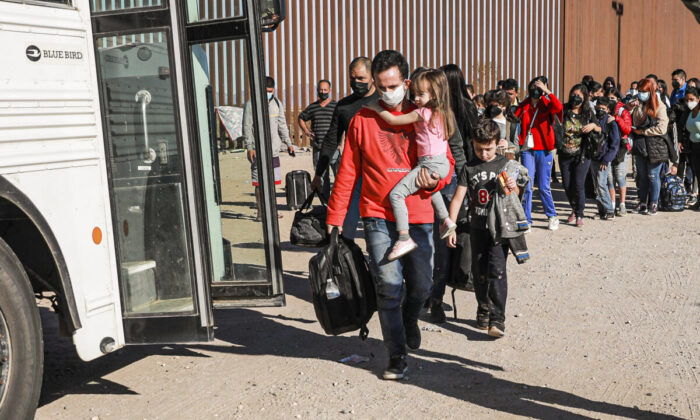 Illegal immigrants who have gathered by the border wall prepare to board a bus going to to the Border Patrol station for processing in Yuma, Ariz., on Dec. 10 2021. (Charlotte Cuthbertson/The Epoch Times)