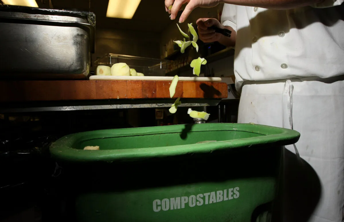 A cook at a restaurant drops apple skins into a food scrap recycling container in San Francisco on April 21, 2009. (Justin Sullivan/Getty Images)