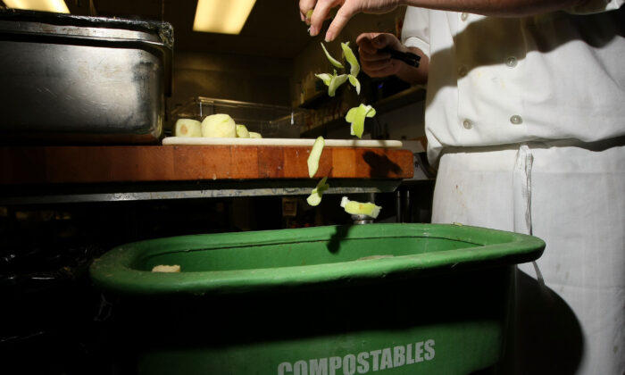A cook at a restaurant drops apple skins into a food scrap recycling container in San Francisco on April 21, 2009. (Justin Sullivan/Getty Images)
