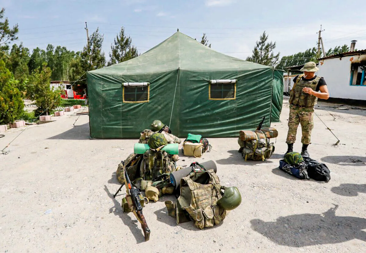 A Kyrgyz border guard smokes outside a temporary camp near a frontier border post in the village of Maksat in Batken province, Kyrgyzstan, on May 4, 2021. (Vladimir Pirogov/Reuters)