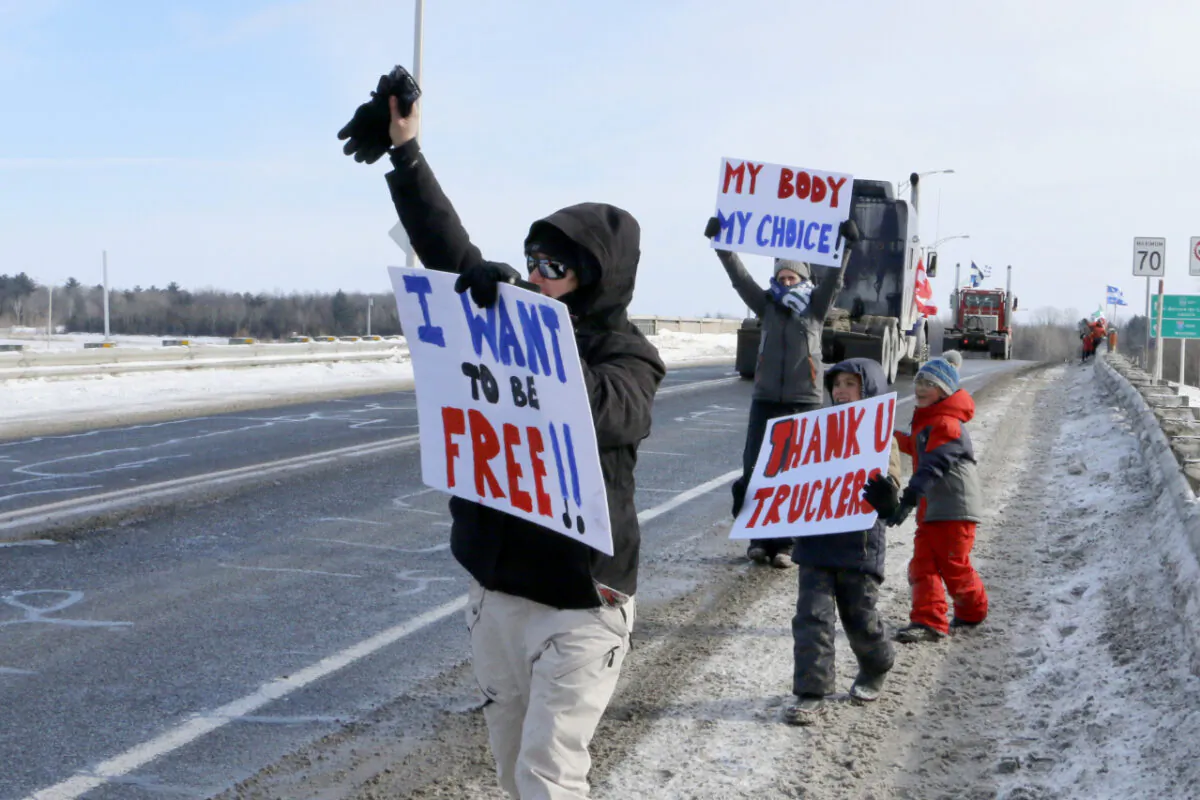 Supporters of the "Freedom Convoy" wave to trucks passing by the south of Montreal on Jan. 28, 2022. (Noé Chartier/The Epoch Times)