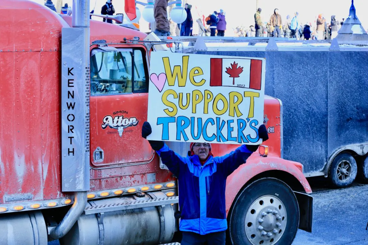 A protester participating in the truck convoy protest against COVID-19 mandates and restrictions holds a sign on Parliament Hill in Ottawa on Jan. 29, 2022. (Jonathan Ren/The Epoch Times)