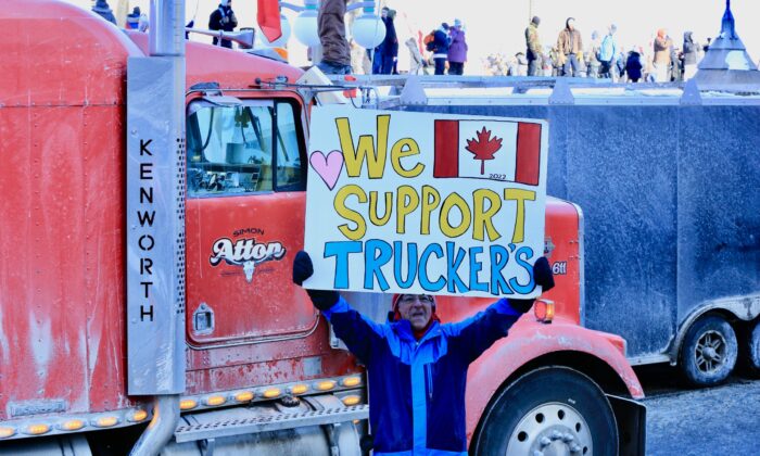 A protester participating in the truck convoy protest against COVID-19 mandates and restrictions holds a sign on Parliament Hill in Ottawa on Jan. 29, 2022. (Jonathan Ren/The Epoch Times)