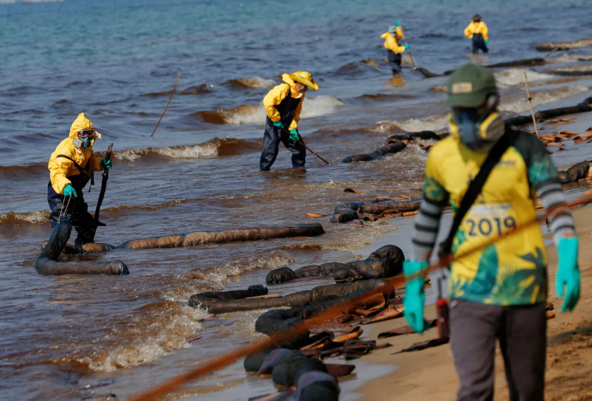Workers clean oil spills caused by a leak from an undersea pipeline 12.4 miles off Thailand's eastern coast at Mae Ramphueng beach in Rayong province, Thailand, on Jan. 29, 2022. (Soe Zeya Tun/Reuters)