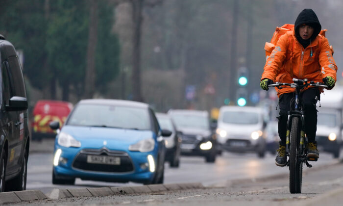 A woman rides along a cycle lane next to heavy traffic in Birmingham, England, on Jan. 25, 2022. (Jacob King/PA)