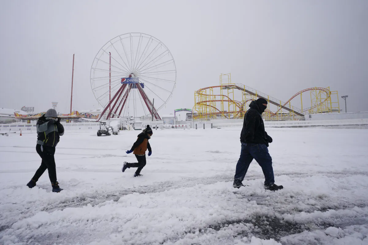 David Bowling (R) walks with his children as they check out the snow near amusement rides along the Ocean City Boardwalk following a snowstorm in Ocean City, Md., on Jan. 29, 2022. (Julio Cortez/AP Photo)