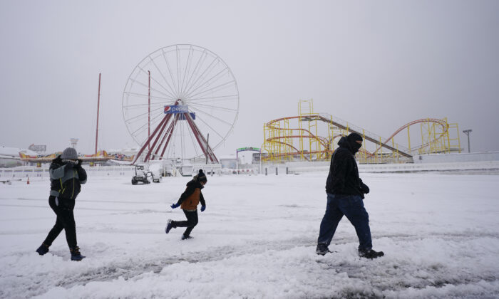 David Bowling (R) walks with his children as they check out the snow near amusement rides along the Ocean City Boardwalk following a snowstorm in Ocean City, Md., on Jan. 29, 2022. (Julio Cortez/AP Photo)