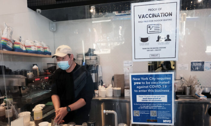 An employee at a coffee shop in Manhattan wears a masks as signs ask for proof of vaccination, on the day that a mask mandate went into effect in New York on Dec. 13, 2021. (Spencer Platt/Getty Images)