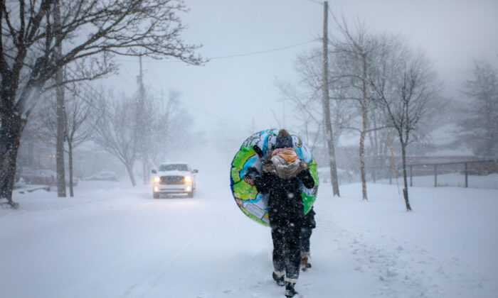 A boy carries a sledding tube through blowing snow during a winter storm in Halifax on Jan. 29, 2022. (The Canadian Press/Kelly Clark)
