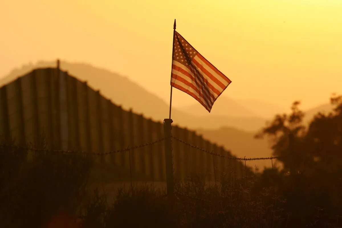 A U.S. flag flies near the U.S.-Mexico border fence in an area where they search for border crossers near Campo, Calif., on Oct. 8, 2006. (David McNew/Getty Images)