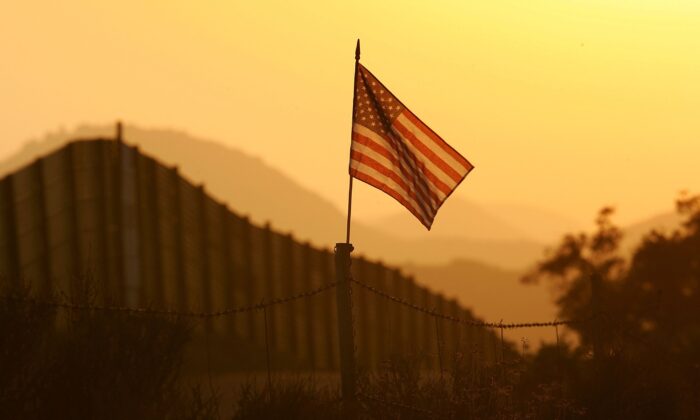 A U.S. flag flies near the U.S.-Mexico border fence in an area where they search for border crossers near Campo, Calif., on Oct. 8, 2006. (David McNew/Getty Images)