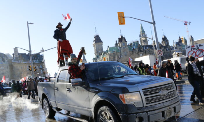2022 年 1 月 29 日，在渥太华举行的自由抗议活动中，一名抗议者骑在皮卡车后部的梯子上。（Noé Chartier/媒体）
