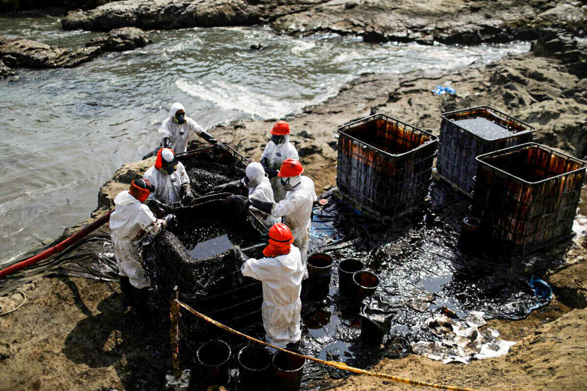 Workers clean up an oil spill following an underwater volcanic eruption in Ventanilla, Peru, on Jan. 25, 2022. (Pilar Olivares/Reuters)