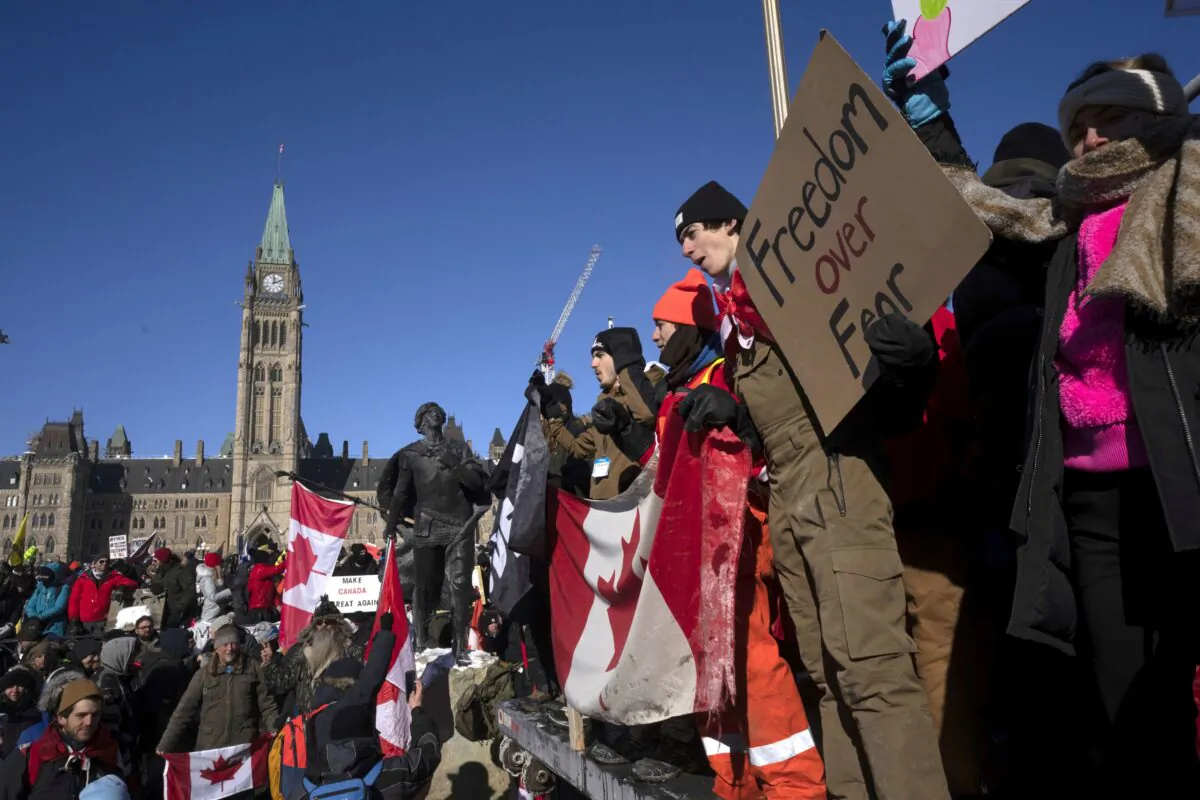 Protesters stand on the back of a truck during the Freedom Convoy demonstrations against COVID-19 vaccine mandates and other restrictions, near Parliament Hill in Ottawa on Jan. 29, 2022. (The Canadian Press/Adrian Wyld)