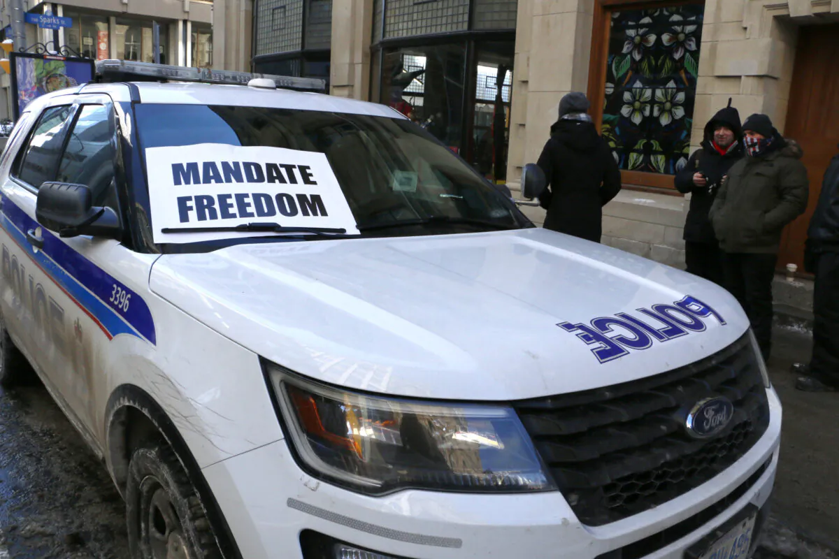A sign is placed on a patrol SUV from the Ottawa Police on Metcalfe St. during protests in Ottawa on Jan. 29, 2022. (Noé Chartier/The Epoch Times)