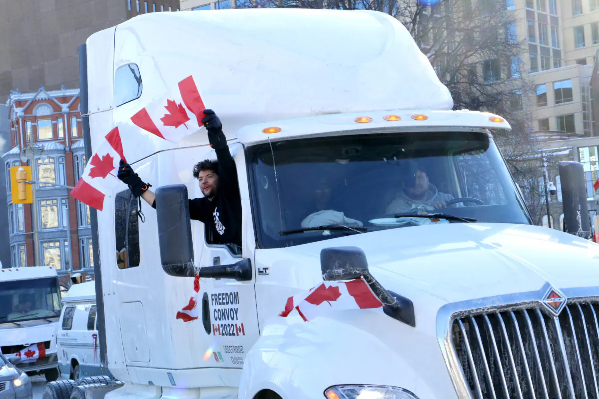 A man waves Canadian flags out of a truck in downtown Ottawa on Jan. 29, 2022. (Noé Chartier/The Epoch Times)
