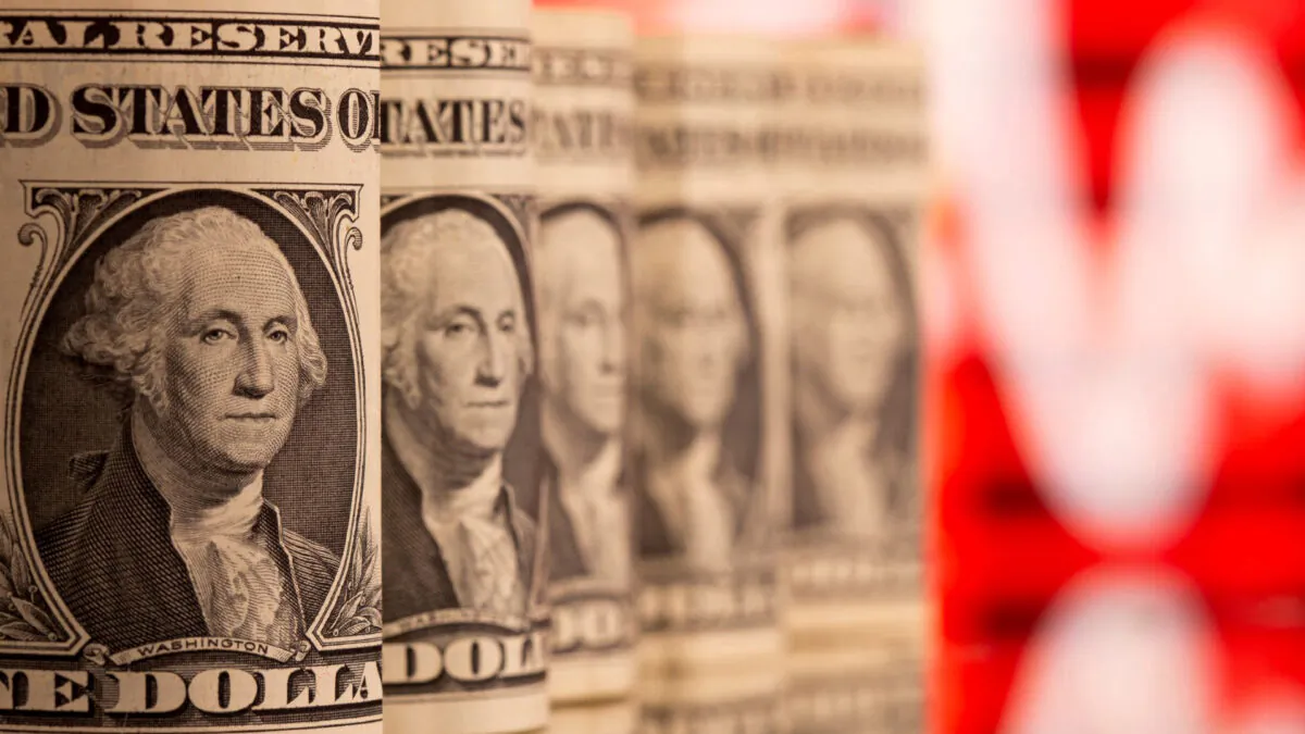 U.S. one dollar banknotes are seen in front of displayed stock graph, on Feb. 8, 2021. (Dado Ruvic/Reuters)