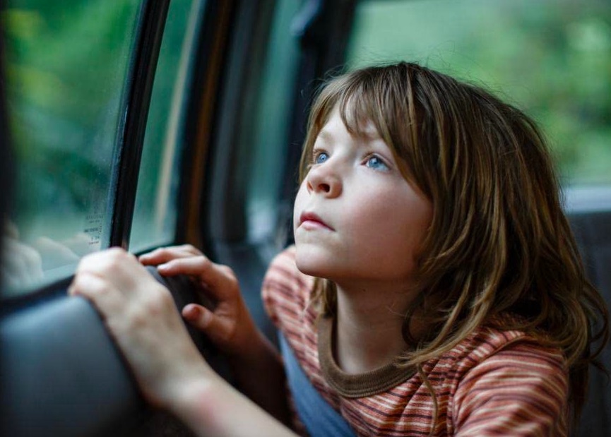 little boy looks out car window in pete's dragon