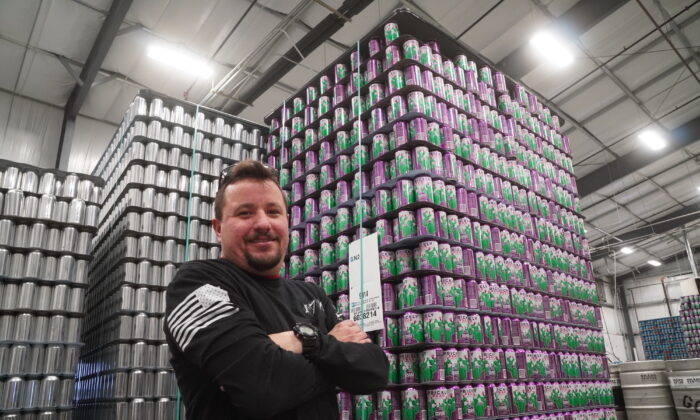 Bret Blanchard, operations manager at Grand Canyon Brewing Co., stands in front of a large inventory of aluminum cans at the company's production facility in Williams, Ariz., on Jan. 17, 2022. (Allan Stein/The Epoch Times)