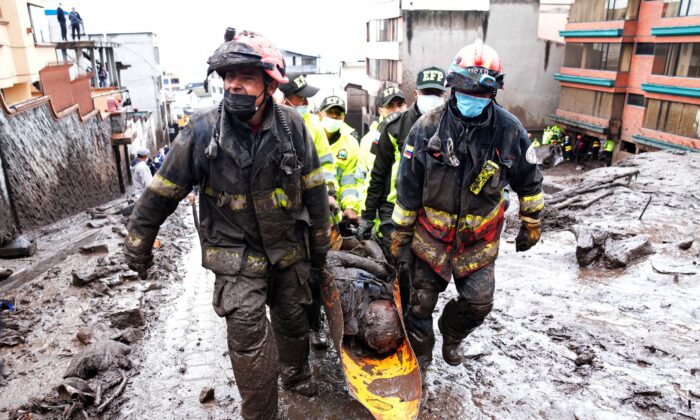 Rescue workers carry away the body of a victim of flash flooding triggered by rain filling up nearby streams that burst their containment mechanisms, collapsing a hillside and bringing waves of mud over homes in La Gasca area of Quito, Ecuador, on Feb. 1, 2022. (Dolores Ochoa/AP Photo)