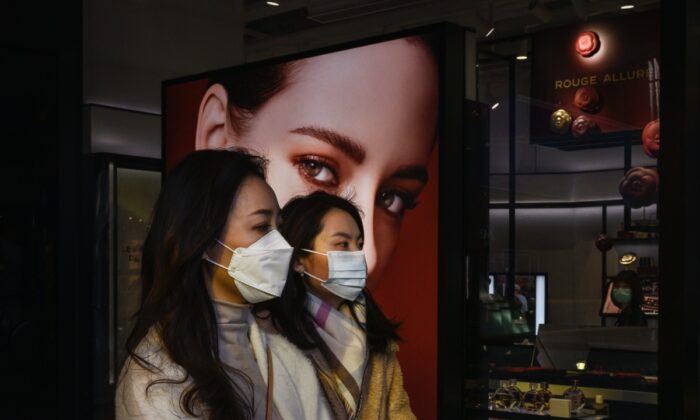 Chinese women wear protective masks as they walk by a luxury store while shopping in Sanlitun on March 10, 2020 in Beijing, China. (Kevin Frayer/Getty Images)