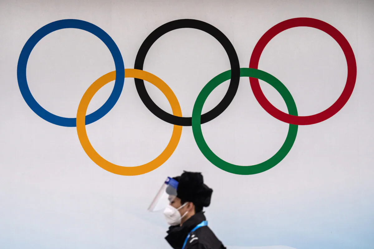 A security official wearing a mask and protective plastic visor walks past Olympic Rings at the National aquatic Centre in Beijing on Jan. 30, 2022. (Carl Court/Getty Images)