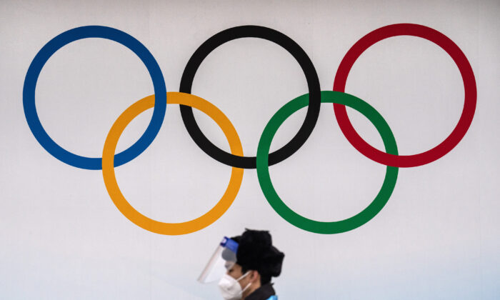 A security official wearing a mask and protective plastic visor walks past Olympic Rings at the National aquatic Centre in Beijing on Jan. 30, 2022. (Carl Court/Getty Images)