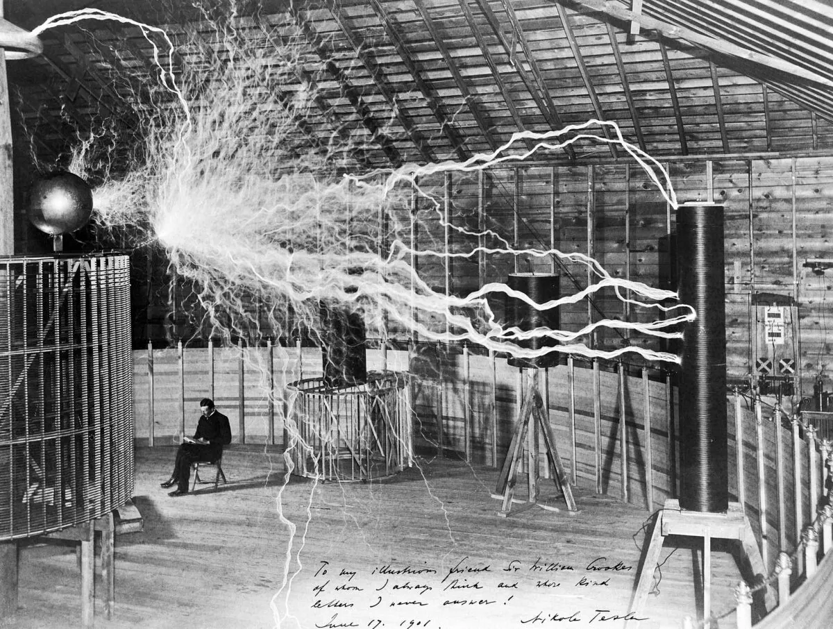 A multiple exposure picture of Nikola Tesla sitting next to his "magnifying transmitter" generating millions of volts. The 23-ft.-long arcs were not part of the normal operation, but only produced for effect by rapidly cycling the power switch. (Public Domain)