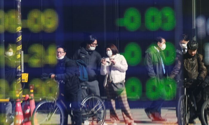 People are reflected on the electronic board of a securities firm in Tokyo, Japan, on Feb. 1, 2022. (Koji Sasahara/AP Photo)