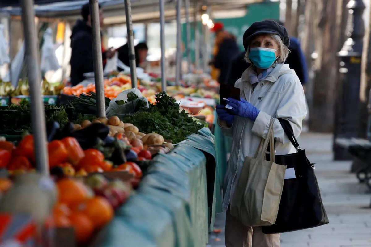 A woman, wearing a protective face mask, shops for fruits and vegetables at the Bastille Market in Paris as a lockdown is imposed to slow the rate of the coronavirus disease (COVID-19) in France, on March 19, 2020. (Gonzalo Fuentes/Reuters)