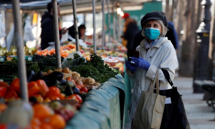A woman, wearing a protective face mask, shops for fruits and vegetables at the Bastille Market in Paris as a lockdown is imposed to slow the rate of the coronavirus disease (COVID-19) in France, on March 19, 2020. (Gonzalo Fuentes/Reuters)