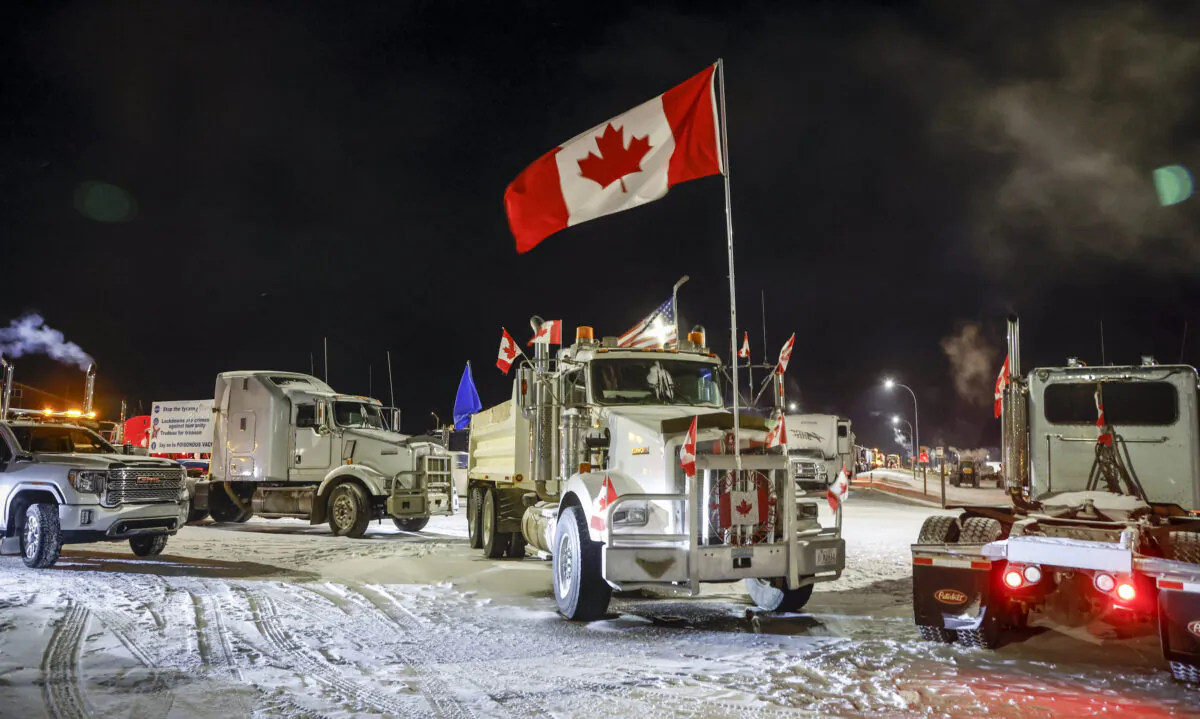 Protesters demonstrating against COVID-19 mandates gather as a truck convoy blocks the highway at the U.S. border crossing in Coutts, Alta., on Feb. 1, 2022. (The Canadian Press/Jeff McIntosh)