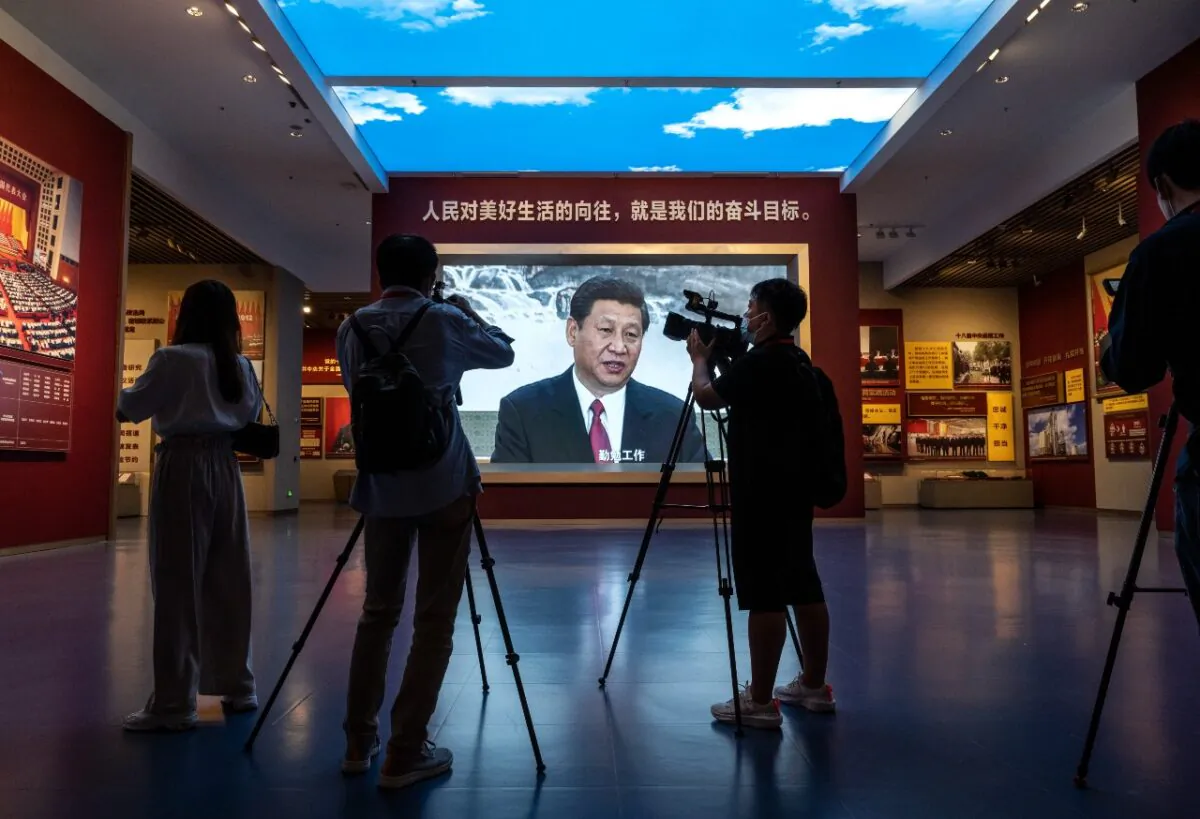 Journalists and others film next to a large screen showing Chinese Communist Party leader Xi Jinping at the newly built Museum of the Communist Party of China on June 25, 2021 in Beijing. (Photo by Kevin Frayer/Getty Images)