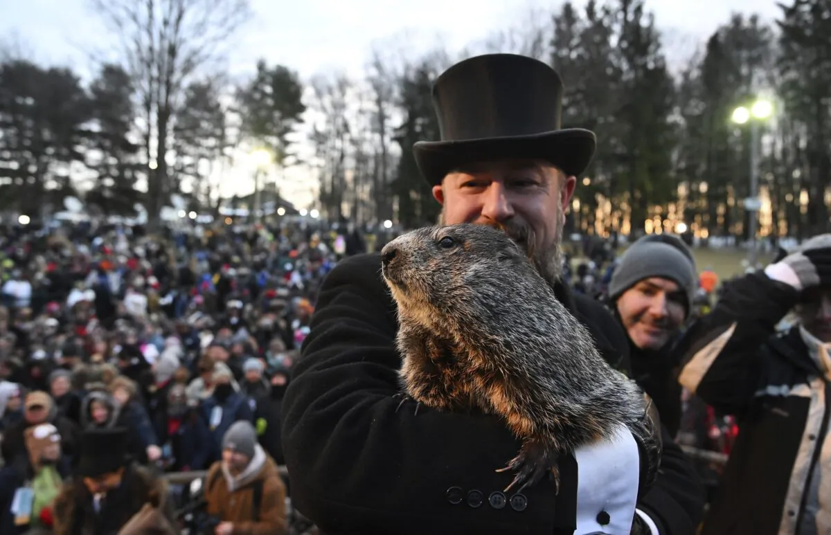 Groundhog Club handler A.J. Dereume interacts with Punxsutawney Phil, the weather prognosticating groundhog, during the 136th celebration of Groundhog Day on Gobbler's Knob in Punxsutawney, Pa., on Feb. 2, 2022. (Barry Reeger/AP Photo)