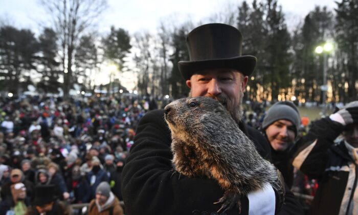Groundhog Club handler A.J. Dereume interacts with Punxsutawney Phil, the weather prognosticating groundhog, during the 136th celebration of Groundhog Day on Gobbler's Knob in Punxsutawney, Pa., on Feb. 2, 2022. (Barry Reeger/AP Photo)
